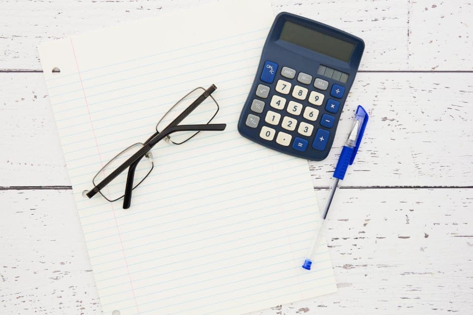 Calculadora, gafas y bolígrafo sobre una hoja en blanco: los elementos para preparar la factura de una consulta de psicología