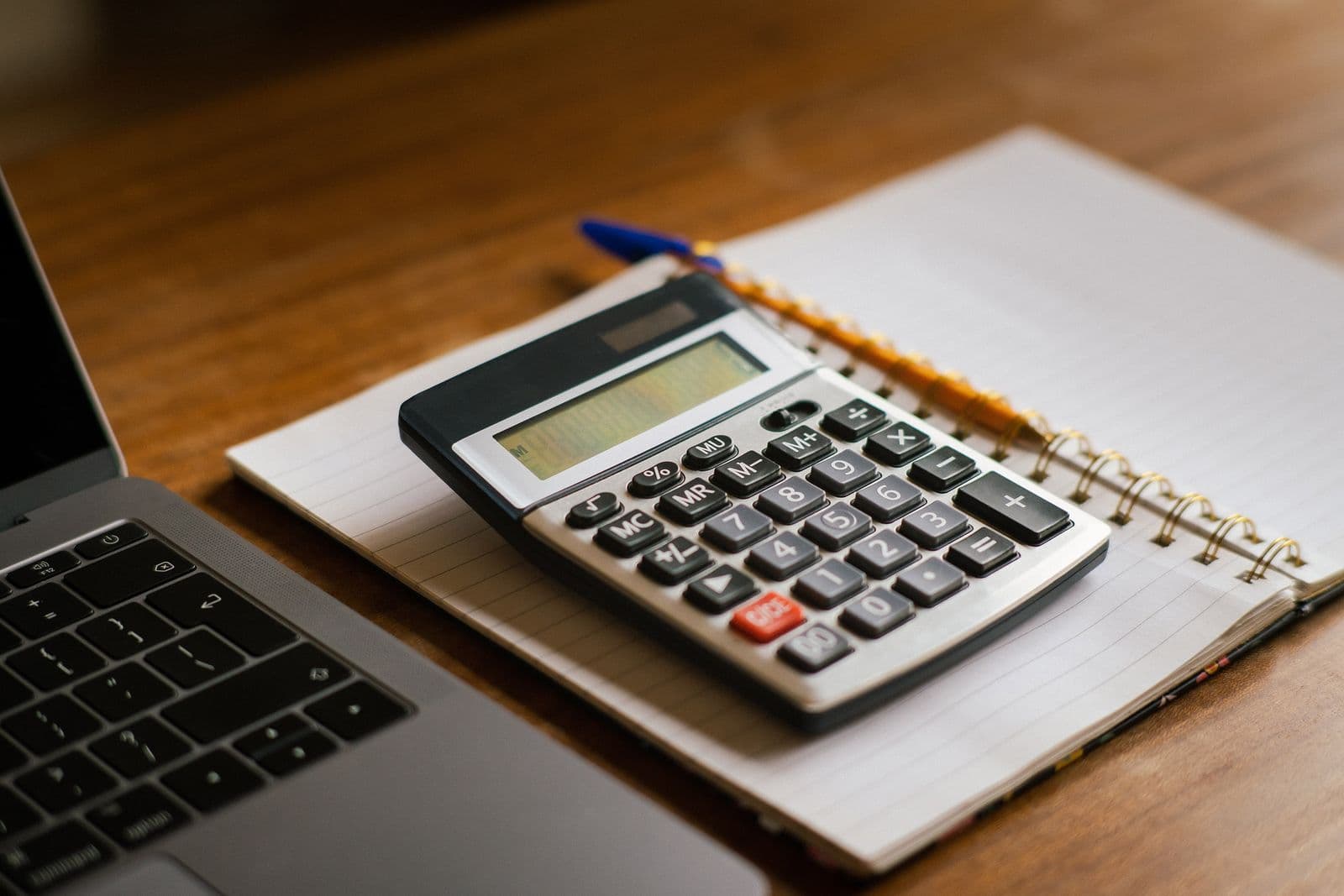 Calculadora sobre un cuaderno junto al portátil: echar cuentas de la sanción de 50.000 € de VeriFactu